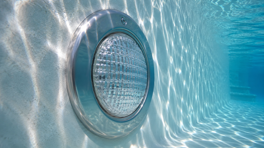 Large round pool light glowing bright white underwater at night with a visible beam