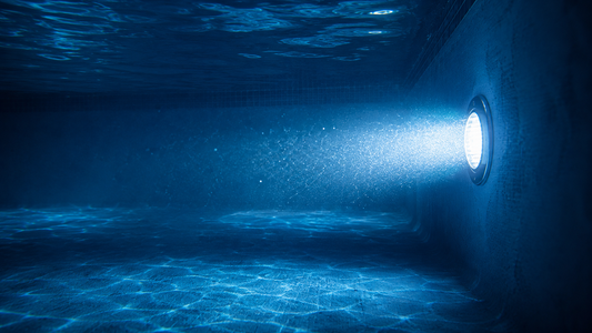 Backyard swimming pool glowing sapphire blue at night from a single LED pool light