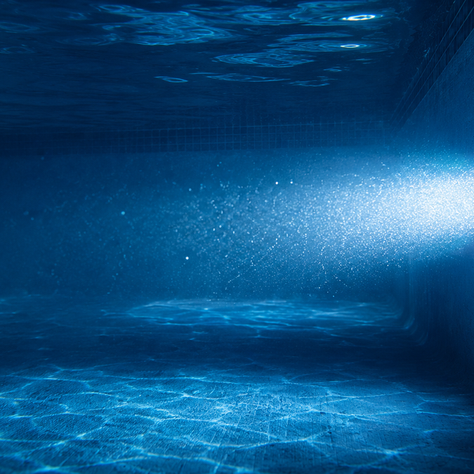Backyard swimming pool glowing sapphire blue at night from a single LED pool light